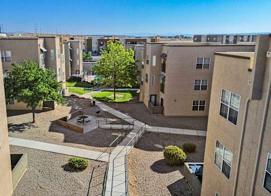 A view of a courtyard from a high angle with a tree, benches, and a small fountain.