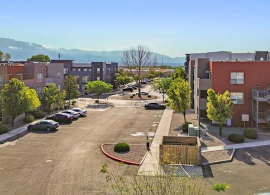 A parking lot with cars and apartment buildings in the background.