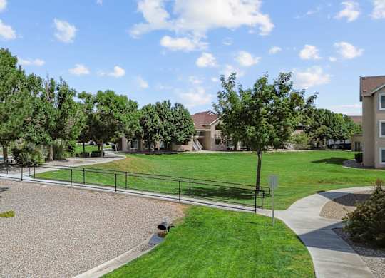 A park area with a gravel playground and a green lawn.