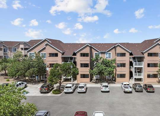 A parking lot in front of a building with cars parked.