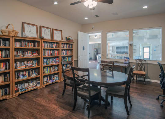 a library with a table and chairs and a book shelf