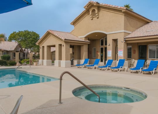 a swimming pool with blue chairs in front of a building