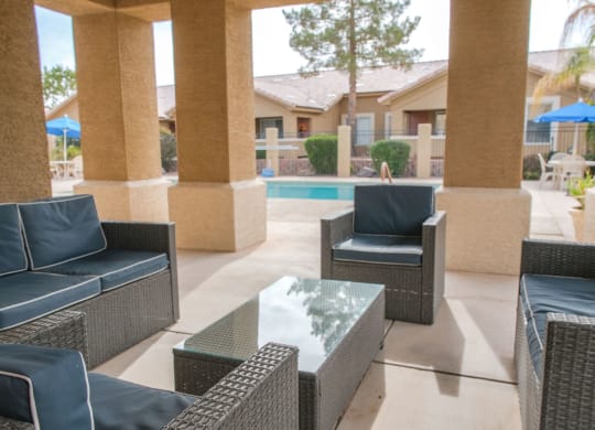 a patio with chairs and a table in front of a pool