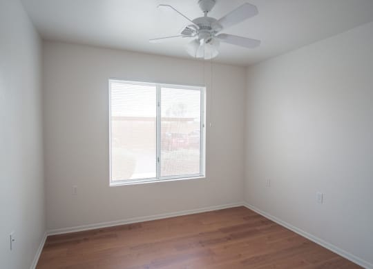 an empty room with a ceiling fan and a window