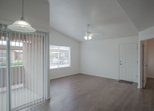 an empty living room with a white door and a ceiling fan