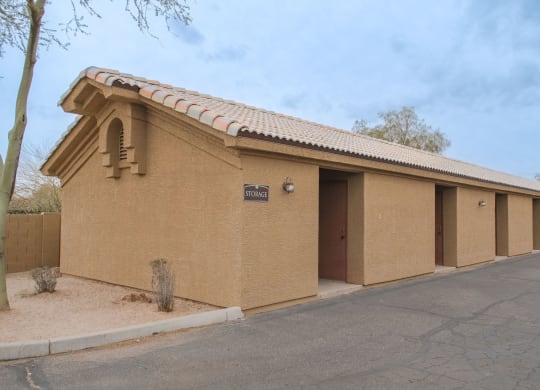 a tan building with three doors and a sidewalk