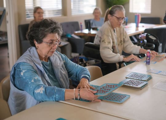 a group of women sitting at a table working on a board game