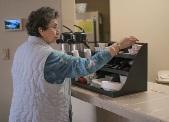 a woman prepares food in a kitchen on a laptop