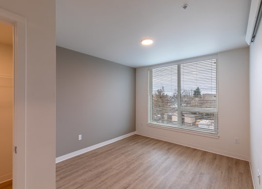 an empty living room with a large window and wood flooring
