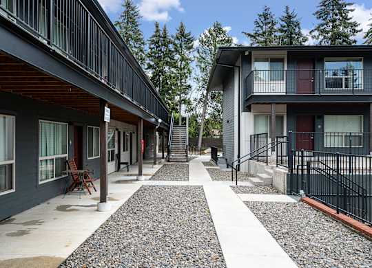 A long, narrow walkway with a black railing separates two buildings.