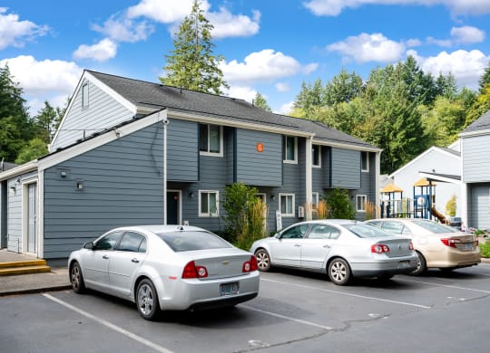 a gray house with cars parked in a parking lot