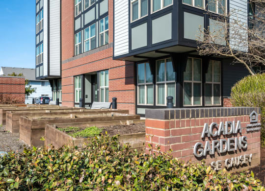 a picture of the front of a building with a sign that reads acadia gardens