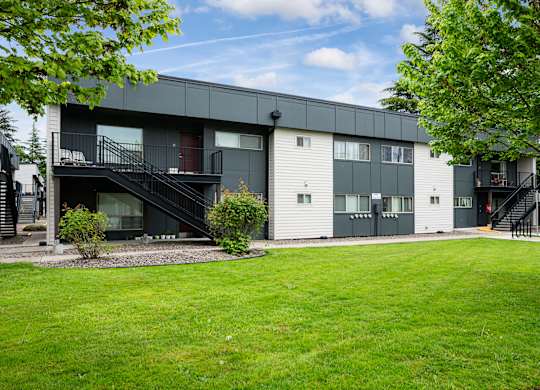 A modern apartment building with a green lawn in front.