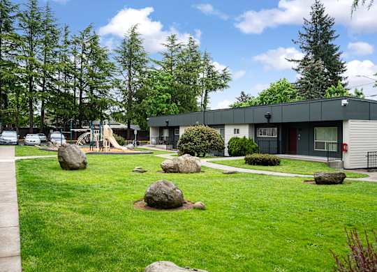 A playground with a slide and a green lawn.