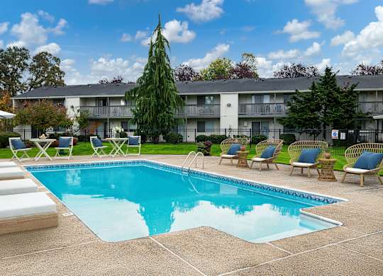 A swimming pool surrounded by lounge chairs and trees.