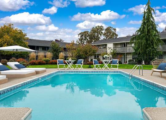 A swimming pool surrounded by lounge chairs and trees.