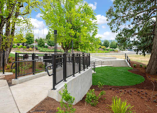 A black metal fence surrounds a green lawn.