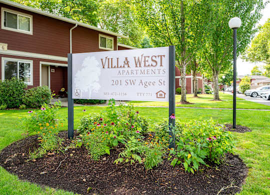 A sign for Villa West Apartments is displayed in front of a building.
