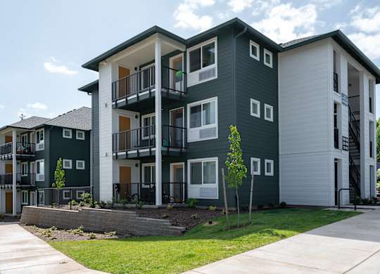 A modern apartment building with balconies and multiple windows.