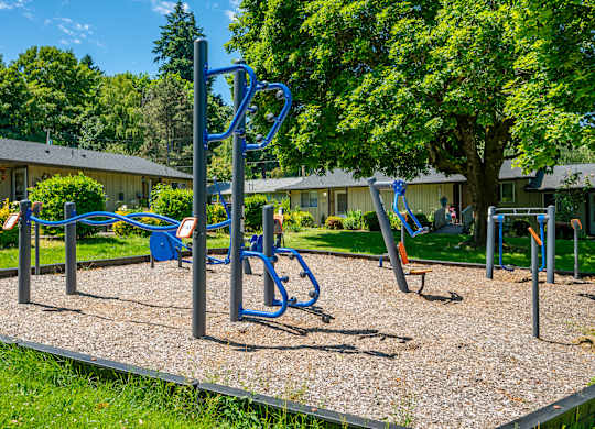 A playground with a blue swing set and a gravel ground.