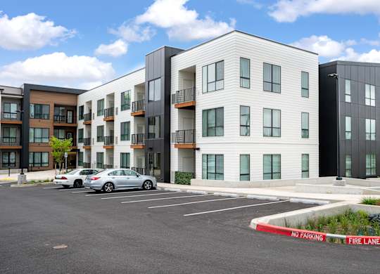 A modern apartment complex with a car parked in the lot.