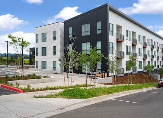 A modern apartment building with a red car driving by.