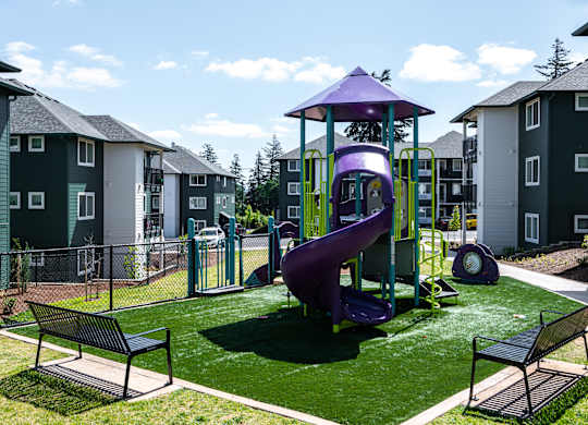 A playground with a purple slide and two benches.