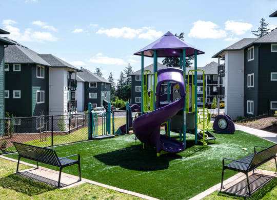 a playground with a purple slide in the middle of an apartment complex