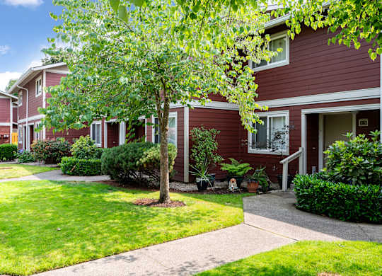 A red house with a tree in front.