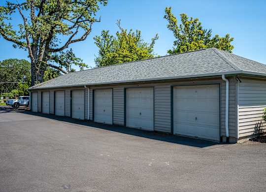 A long building with a grey roof and white garage doors.