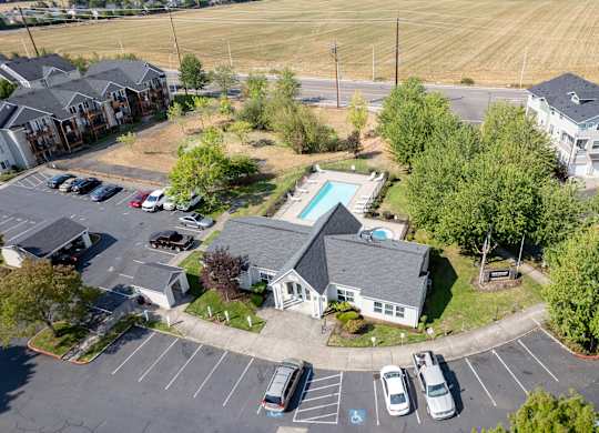 A parking lot with a few cars and a building with a pool in the background.