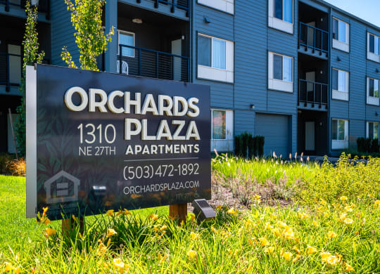 a sign sits in the grass in front of an apartment building