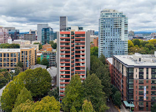 A cityscape with a mix of modern and older buildings, with trees in the foreground.