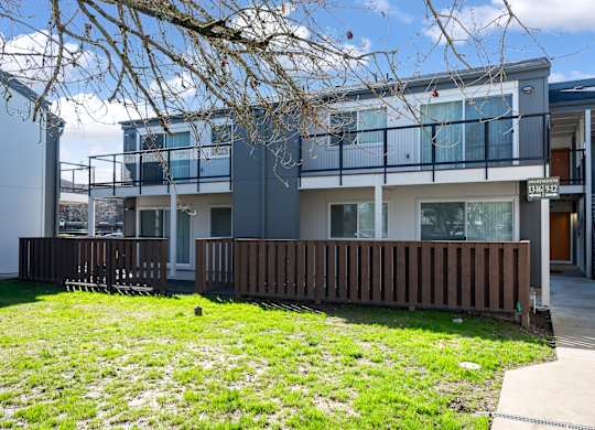 A modern two-story house with a balcony and a deck.