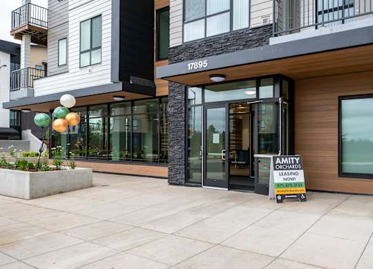A modern building with a leasing sign in front.