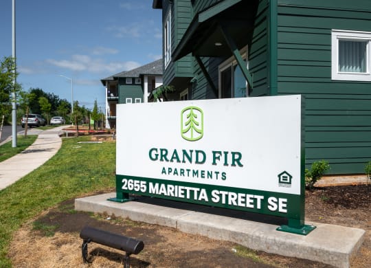 a sign for grand fir apartments in front of a green building