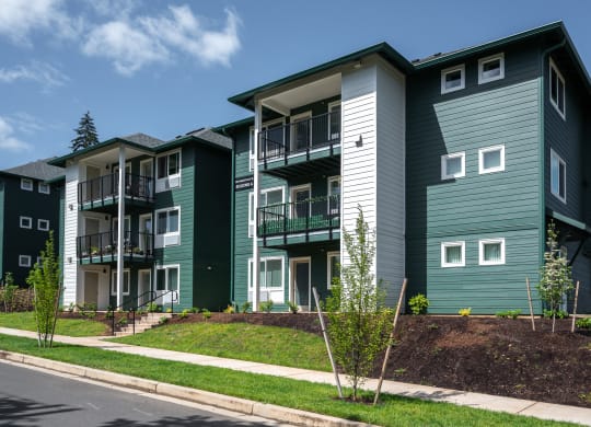 a row of green and white apartment buildings on the side of a street
