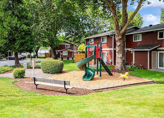 A playground with a green slide and a yellow duck in the foreground.