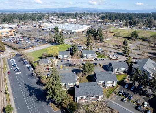 A bird's eye view of a parking lot with cars and buildings.