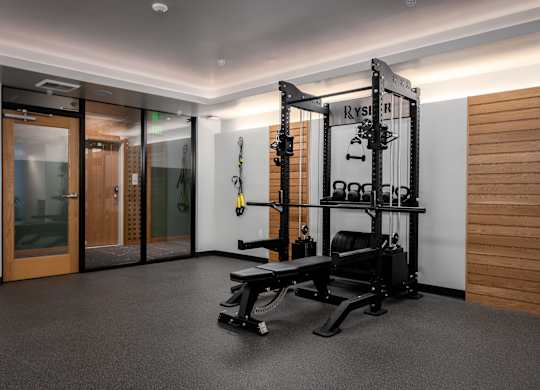 A gym room with a squat rack and a bench.