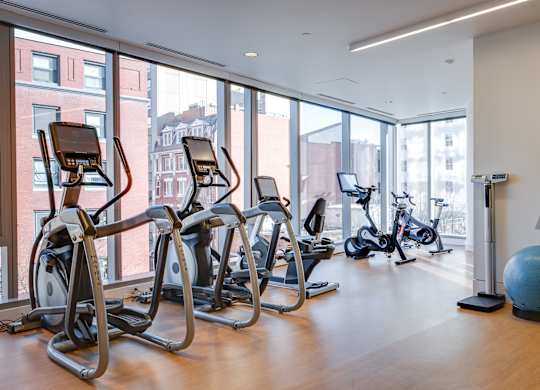 A gym with treadmills, exercise bikes and a large ball.