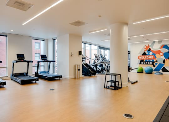 A gym with treadmills, exercise balls, and a ropes sign.