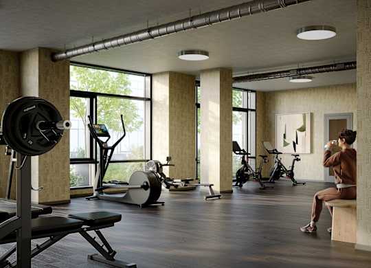 A person is sitting on a bench in a gym with a barbell on a squat rack.