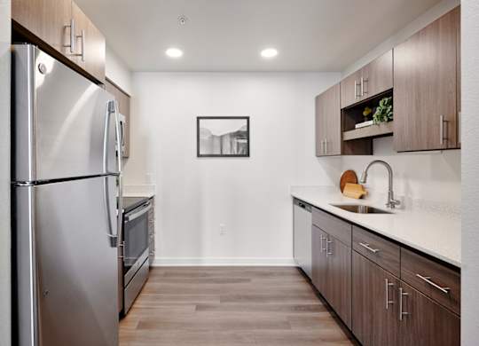 A modern kitchen with a refrigerator, oven, and sink.