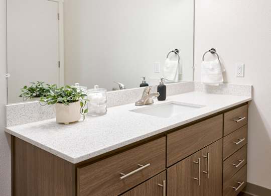 A bathroom with a white countertop and brown cabinets.