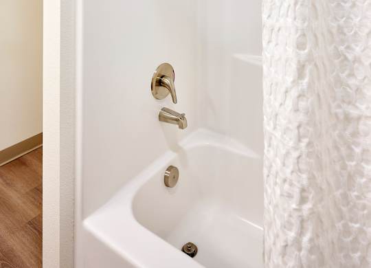 A white bathroom with a white tub and a white shower curtain.