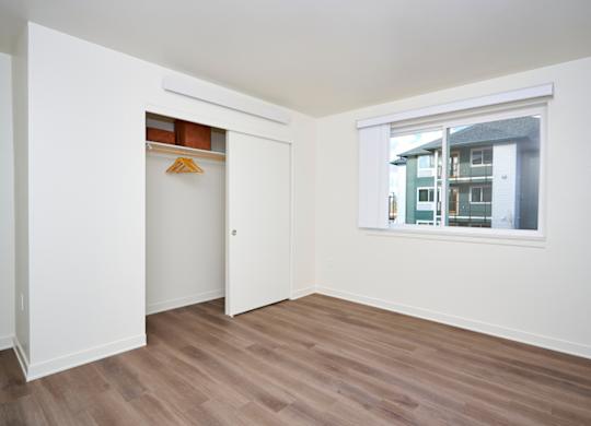 A room with a white door and a window showing a building outside.
