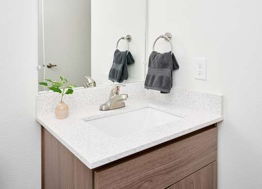 A bathroom vanity with a white countertop and a mirror above it.