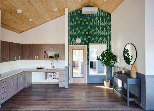 A kitchen with a green patterned wallpaper and wooden cabinets.
