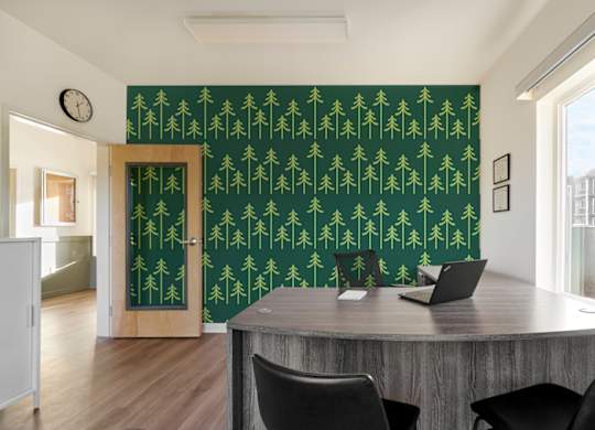 A room with a green wallpaper and a wooden table with chairs.